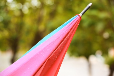 Photo of Bright folded umbrella under rain on street, closeup