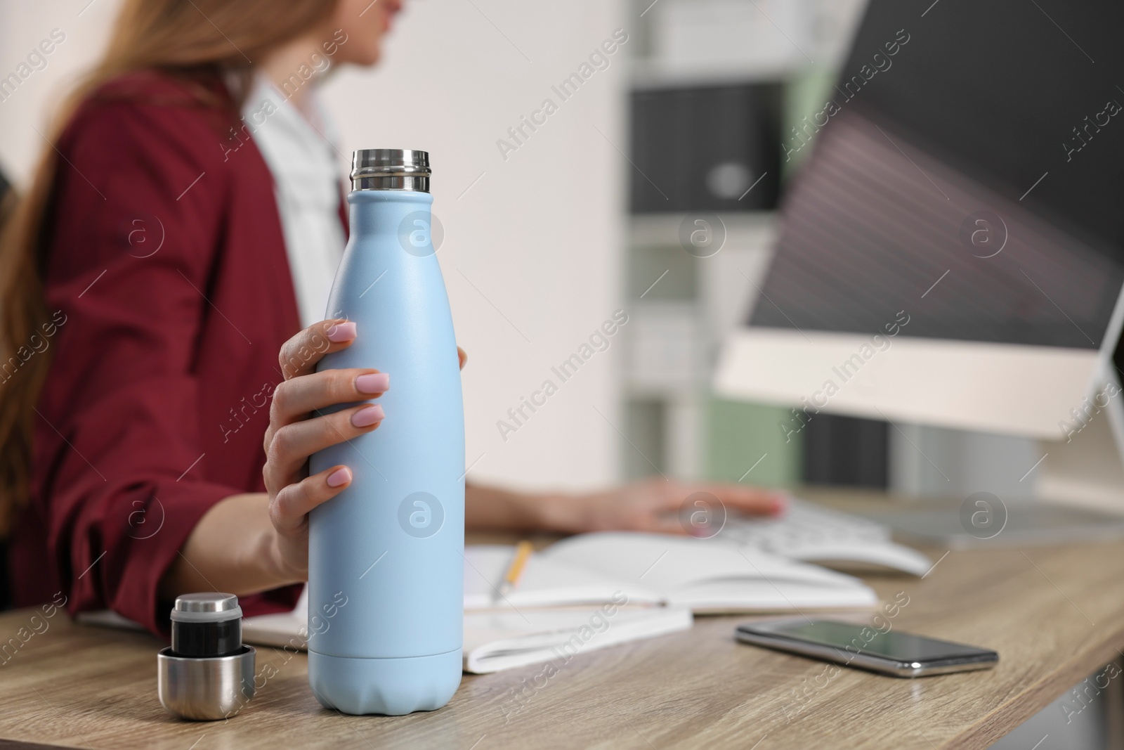Photo of Woman holding thermos bottle at workplace, closeup. Space for text