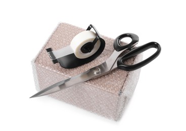 Cardboard box packed in bubble wrap, scissors and adhesive tape on white background