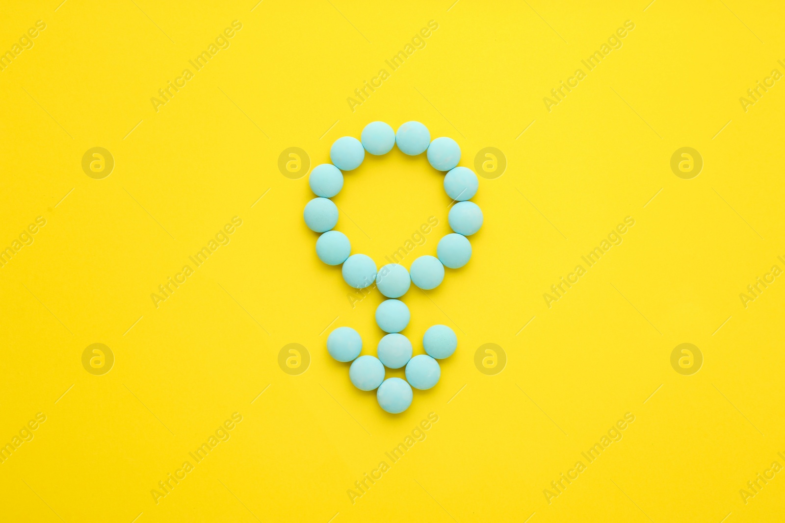 Photo of Male sign made of blue pills on yellow background, flat lay. Potency problems