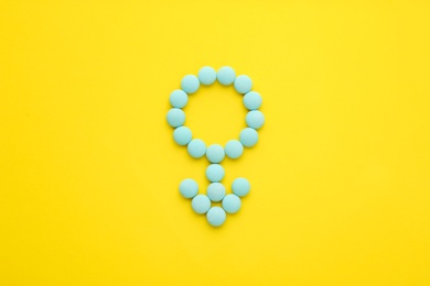 Male sign made of blue pills on yellow background, flat lay. Potency problems