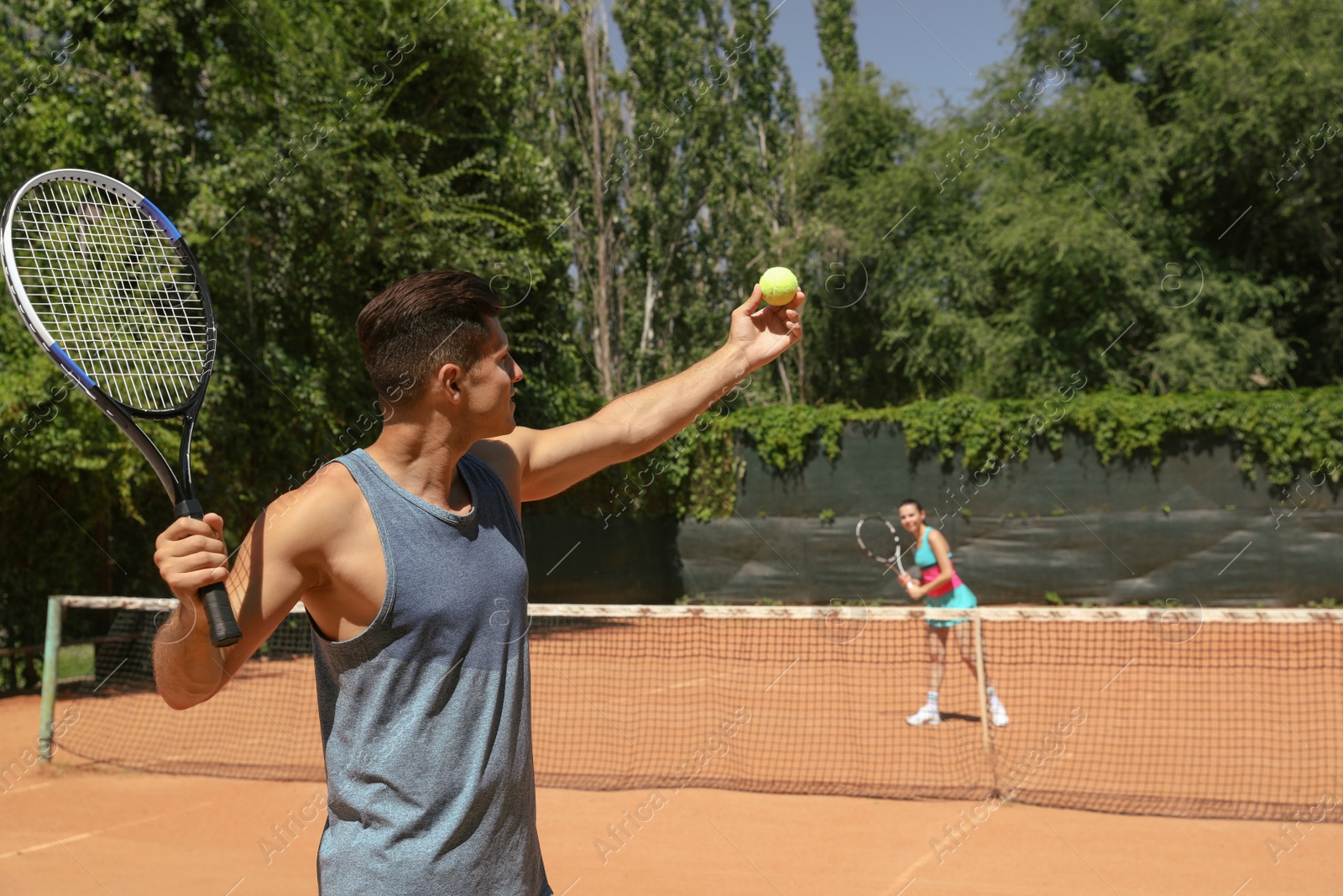 Photo of Couple playing tennis on court during sunny day