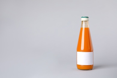 Photo of Tasty drink in bottle with blank label on color background. Mock up for design