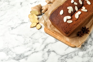 Photo of Delicious gingerbread cake with almond petals on white marble table, above view. Space for text