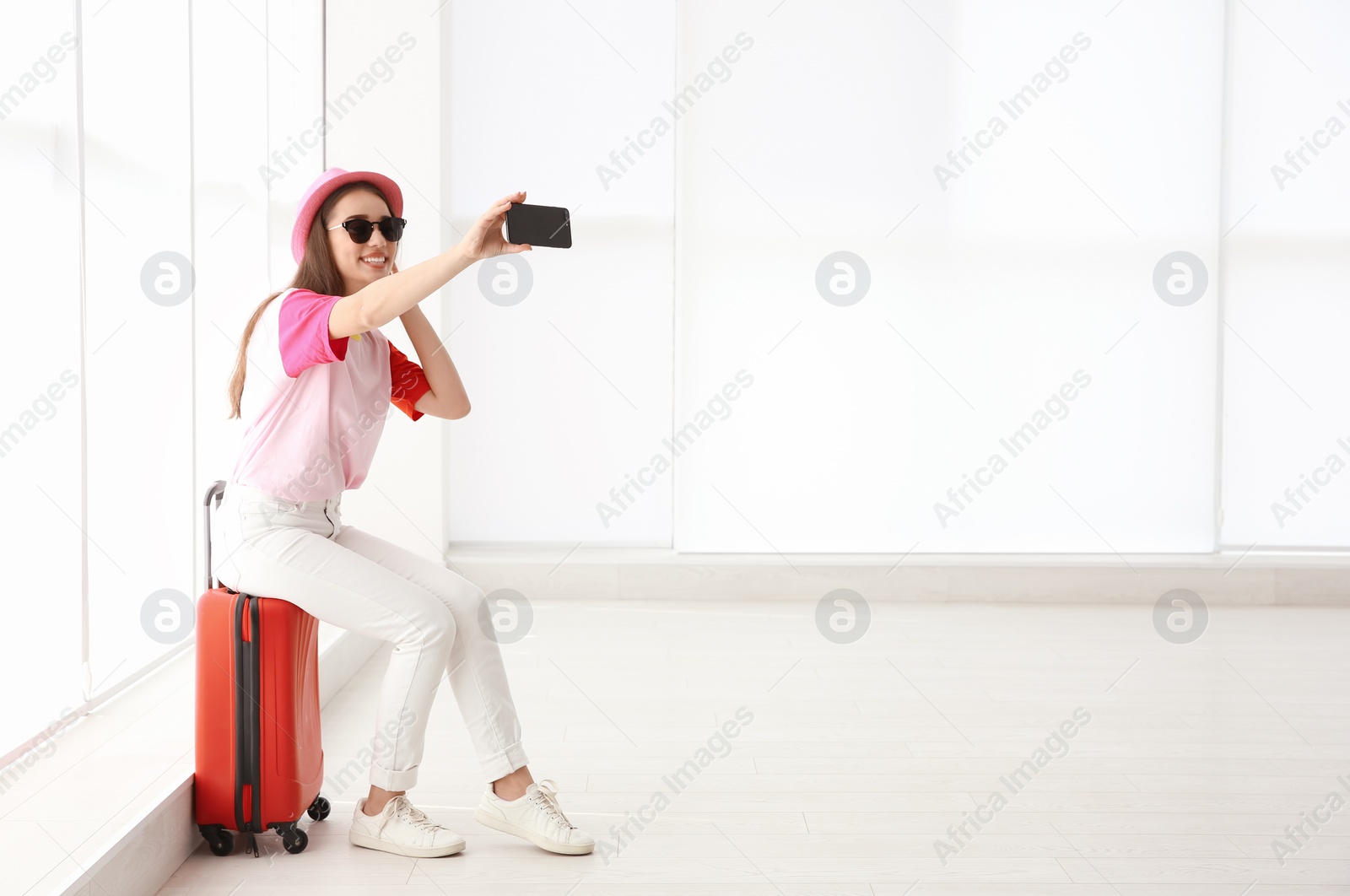 Photo of Young woman sitting on suitcase in airport