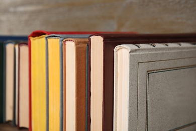 Photo of Stack of hardcover books on wooden background, closeup