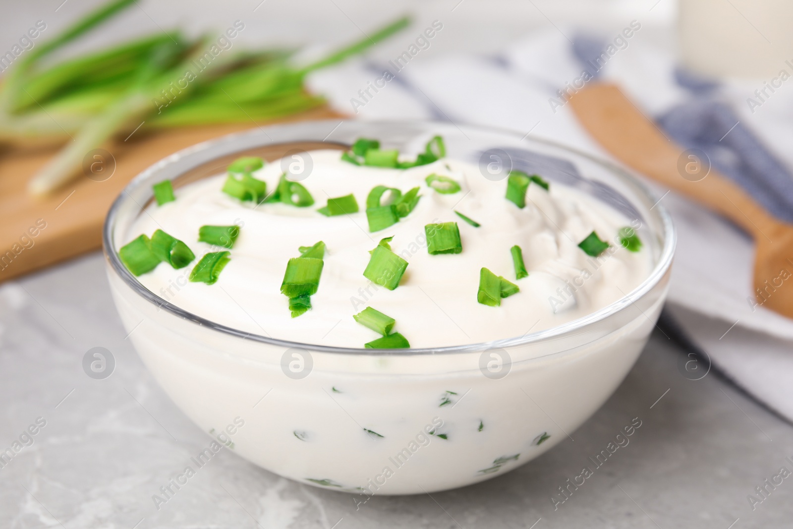 Photo of Fresh sour cream with onion on grey marble table, closeup