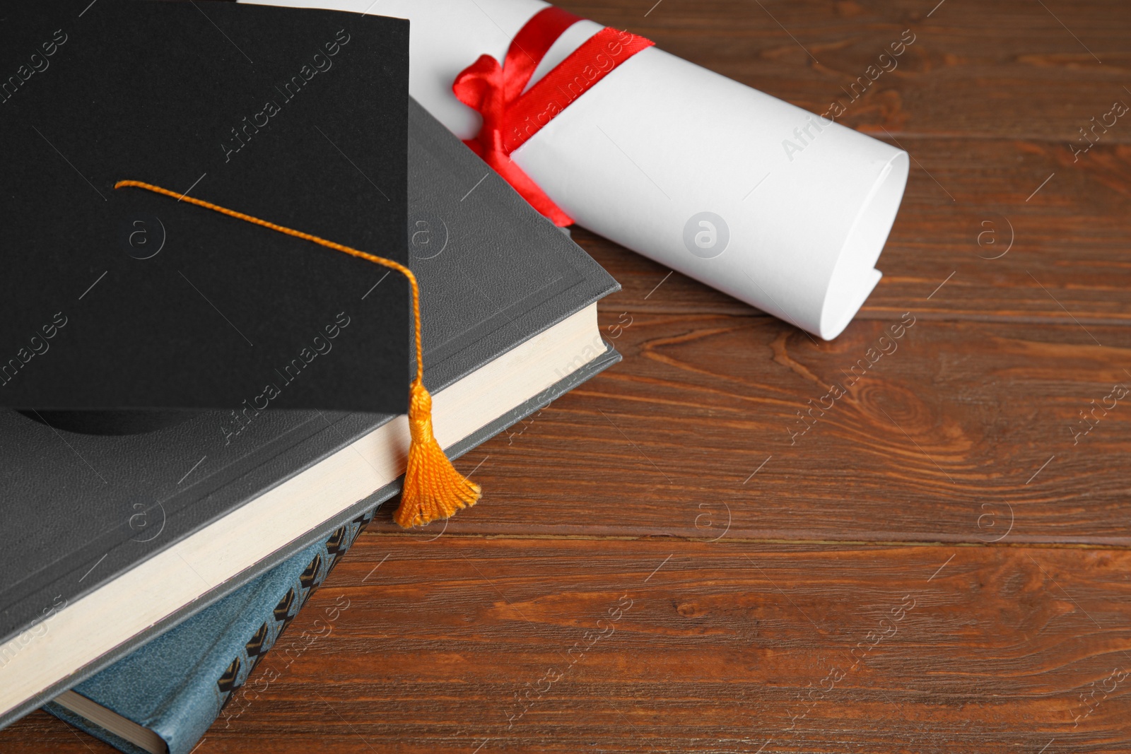 Photo of Graduation hat, books and student's diploma on wooden table