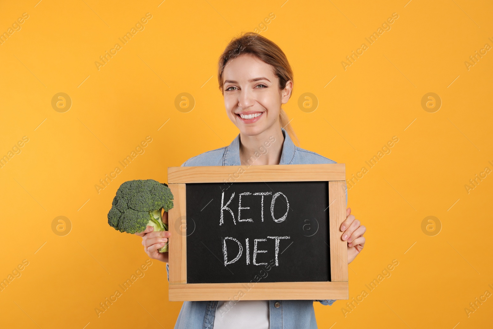 Photo of Woman holding blackboard with phrase Keto Diet and broccoli on yellow background