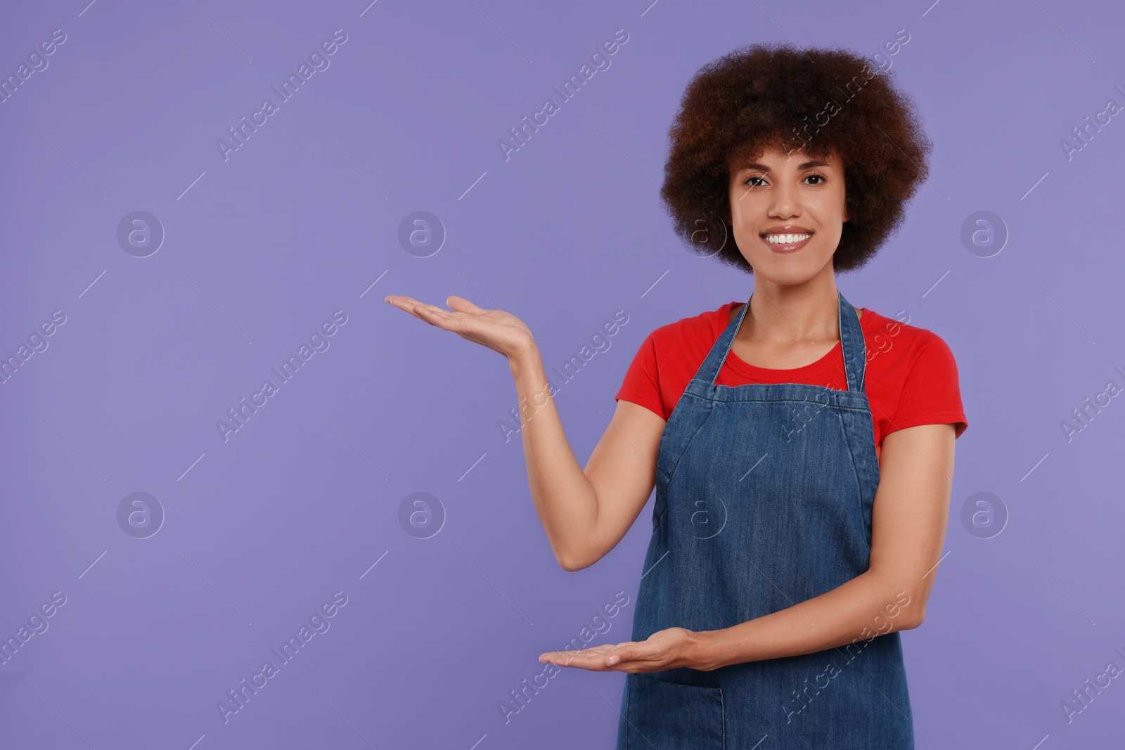 Photo of Portrait of happy young woman in apron on purple background. Space for text