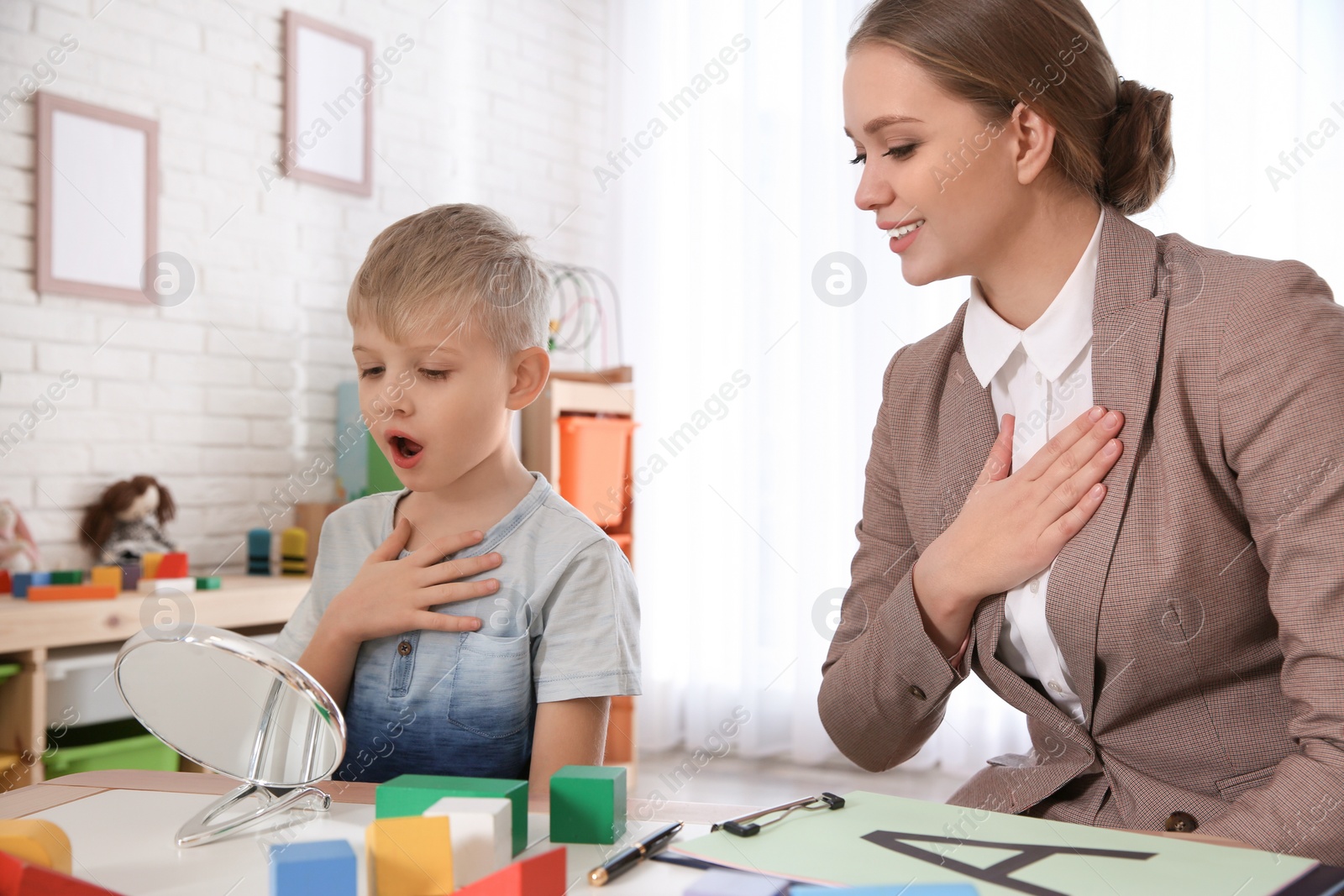 Photo of Speech therapist working with little boy in office