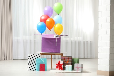 Gift box with bright air balloons and gift bags indoors