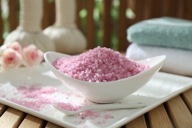 Photo of Bowl of pink sea salt on wooden table, closeup