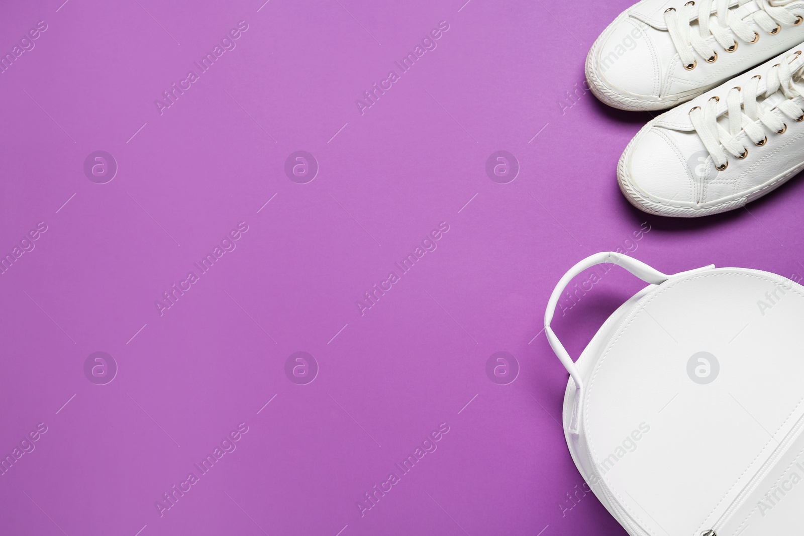 Photo of Stylish casual backpack and sneakers on purple background, flat lay. Space for text