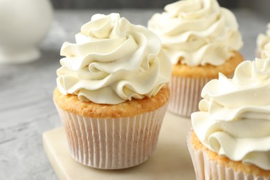 Photo of Tasty cupcakes with vanilla cream on grey table, closeup