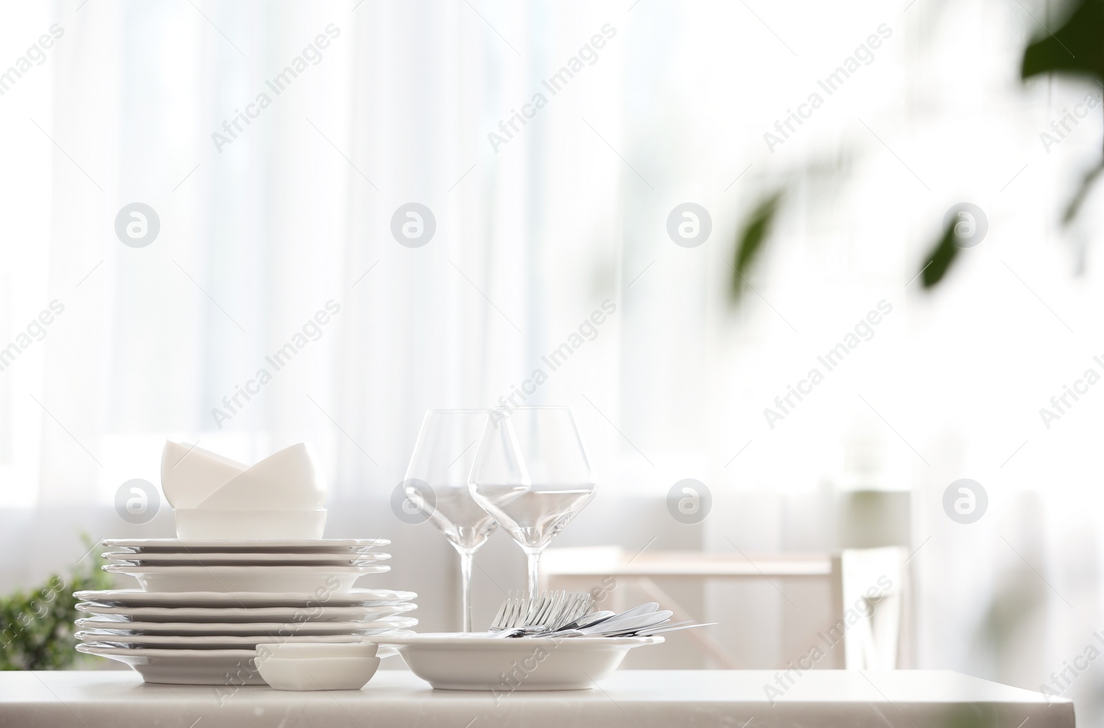 Photo of Set of clean dishware, cutlery and wineglasses on table indoors. Space for text