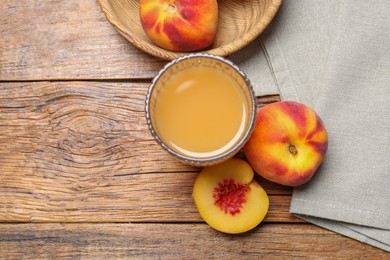 Photo of Glass of peach juice and fresh fruits on wooden table, flat lay. Space for text