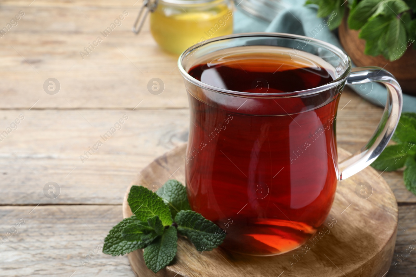 Photo of Cup of hot aromatic tea with mint on wooden table, closeup