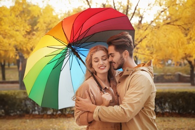 Happy couple with colorful umbrella in park