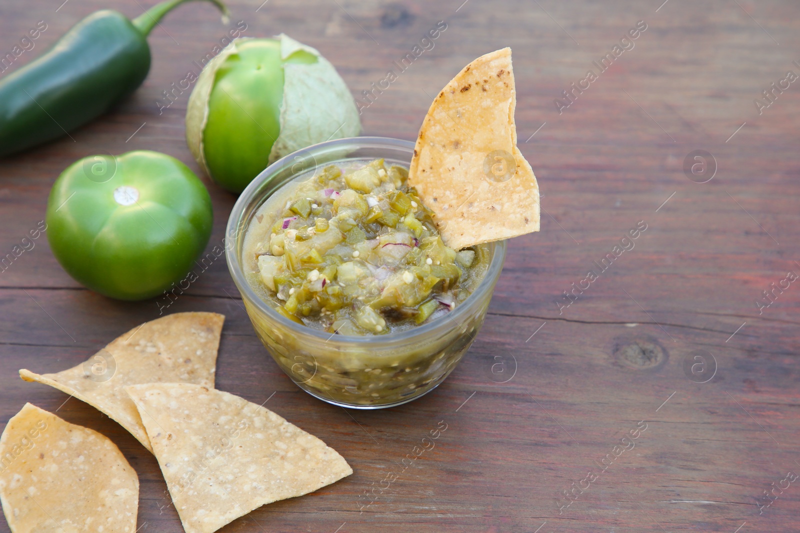 Photo of Tasty salsa sauce, ingredients and tortilla chips on wooden table, closeup. Space for text
