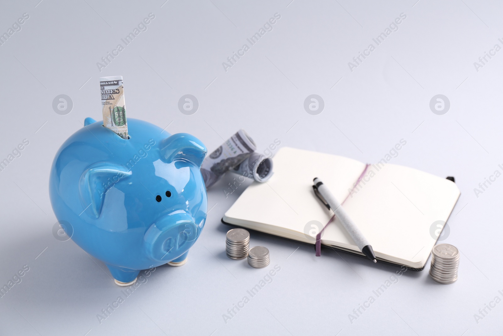 Photo of Financial savings. Piggy bank, dollar banknotes, coins and stationery on grey background