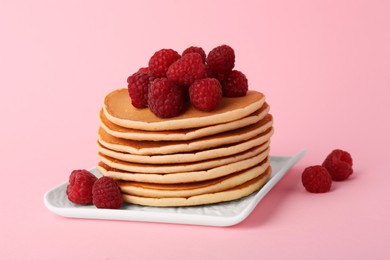 Photo of Stack of tasty pancakes with raspberries on pink background