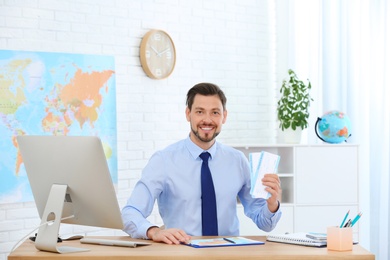 Photo of Male consultant holding tickets in travel agency