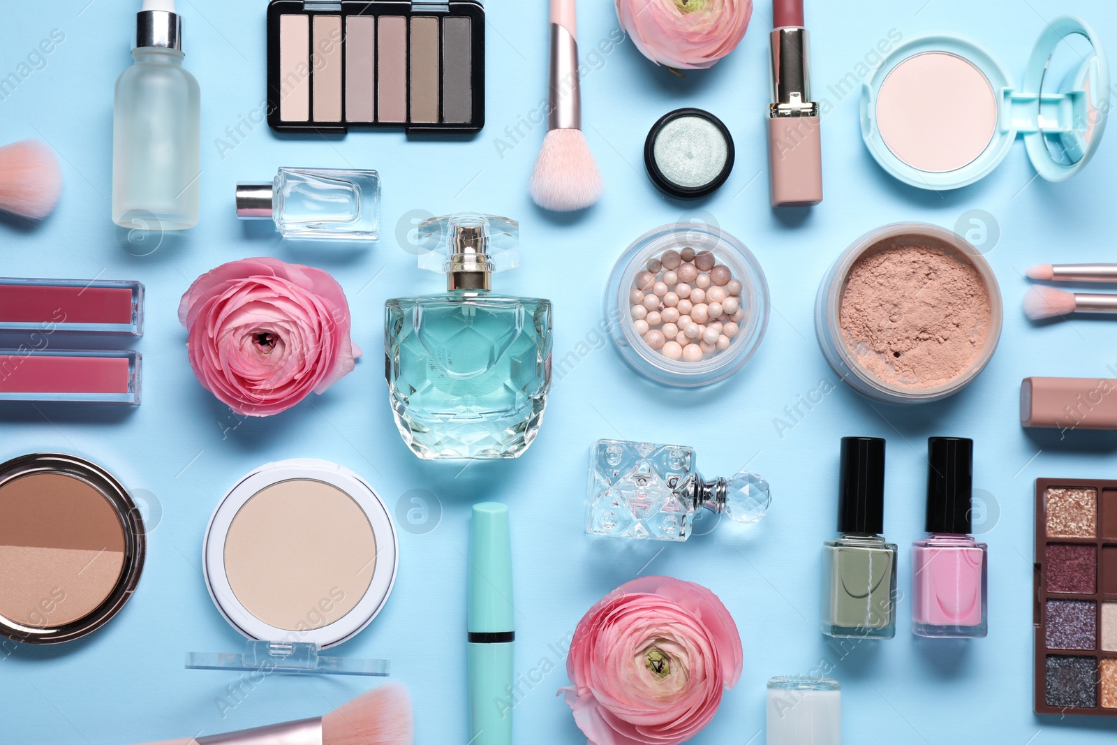 Photo of Flat lay composition with different makeup products and beautiful spring flowers on light blue background