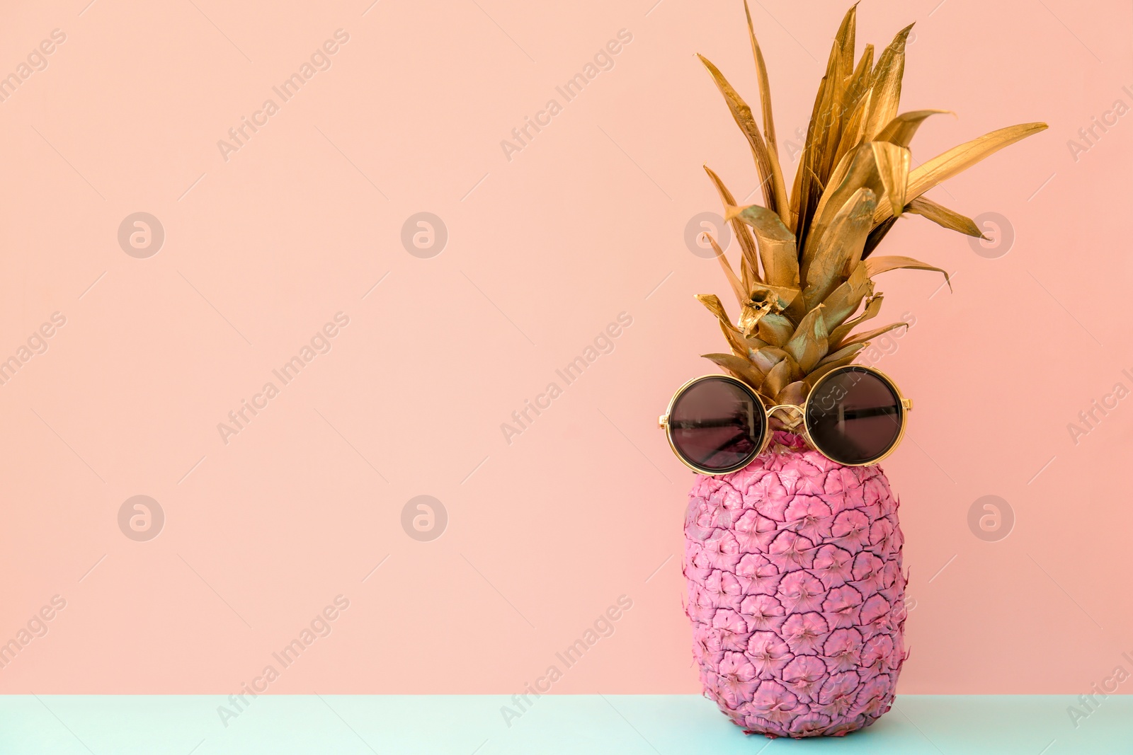 Photo of Pink pineapple with sunglasses on color background