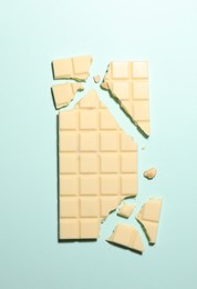 Delicious white chocolate on turquoise background, top view