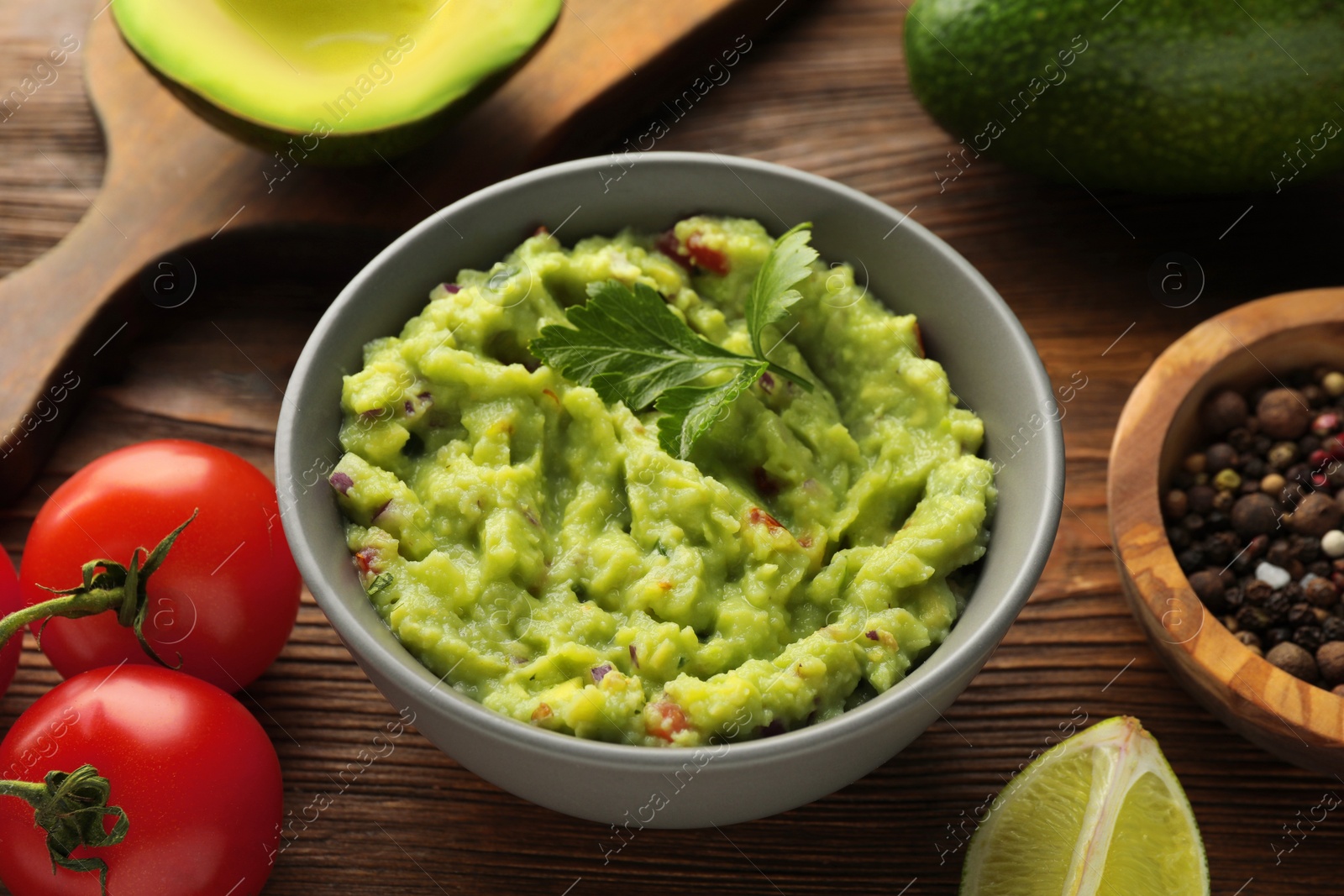 Photo of Delicious guacamole and ingredients on wooden table