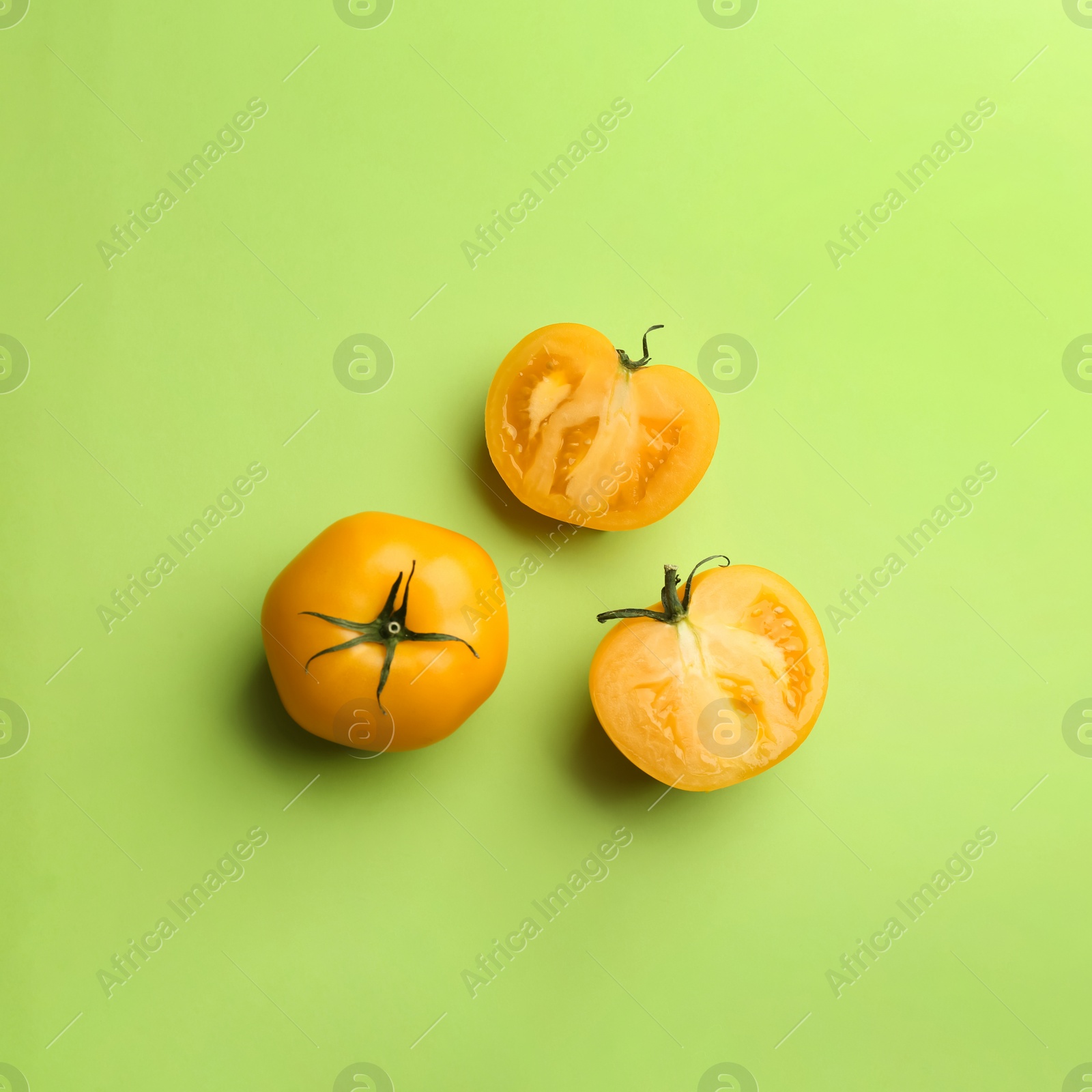 Photo of Yellow tomatoes on green background, flat lay