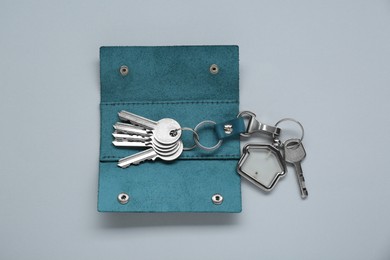 Photo of Open leather holder with keys on light grey background, top view
