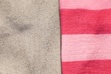 Soft pink beach towel on sand, top view. Space for text