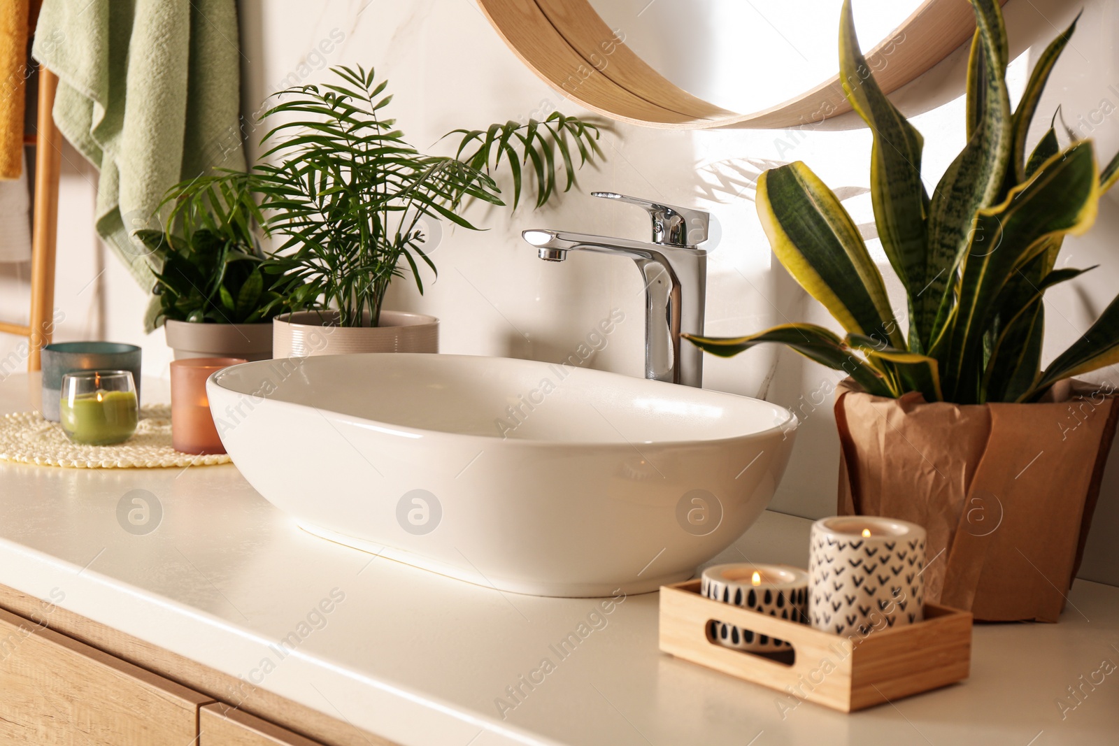Photo of Bathroom counter with sink, candles and beautiful green houseplants near white marble wall