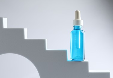 Photo of Bottle of luxury serum on stairs against white background