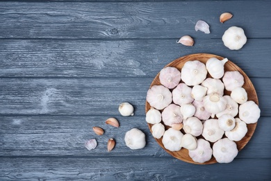 Photo of Plate with fresh garlic bulbs on wooden background, top view