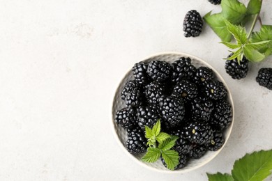 Photo of Tasty ripe blackberries and leaves on white table, flat lay. Space for text