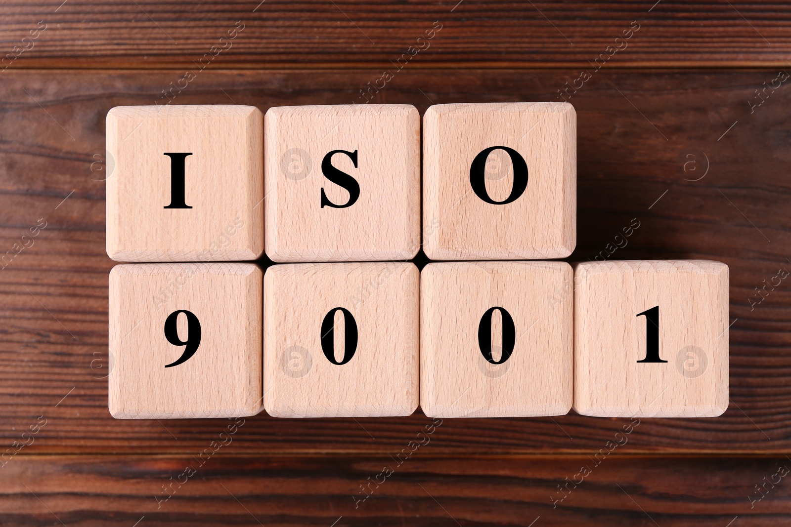 Photo of Cubes with abbreviation ISO and number 9001 on wooden table, flat lay