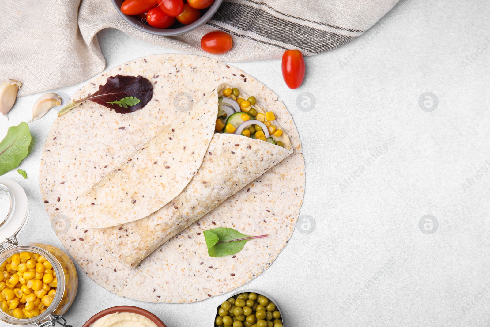 Photo of Delicious hummus wrap with vegetables on light table, flat lay. Space for text