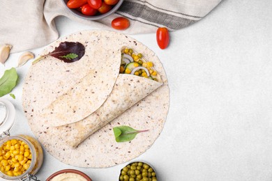 Photo of Delicious hummus wrap with vegetables on light table, flat lay. Space for text