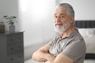 Portrait of handsome senior man at home, space for text