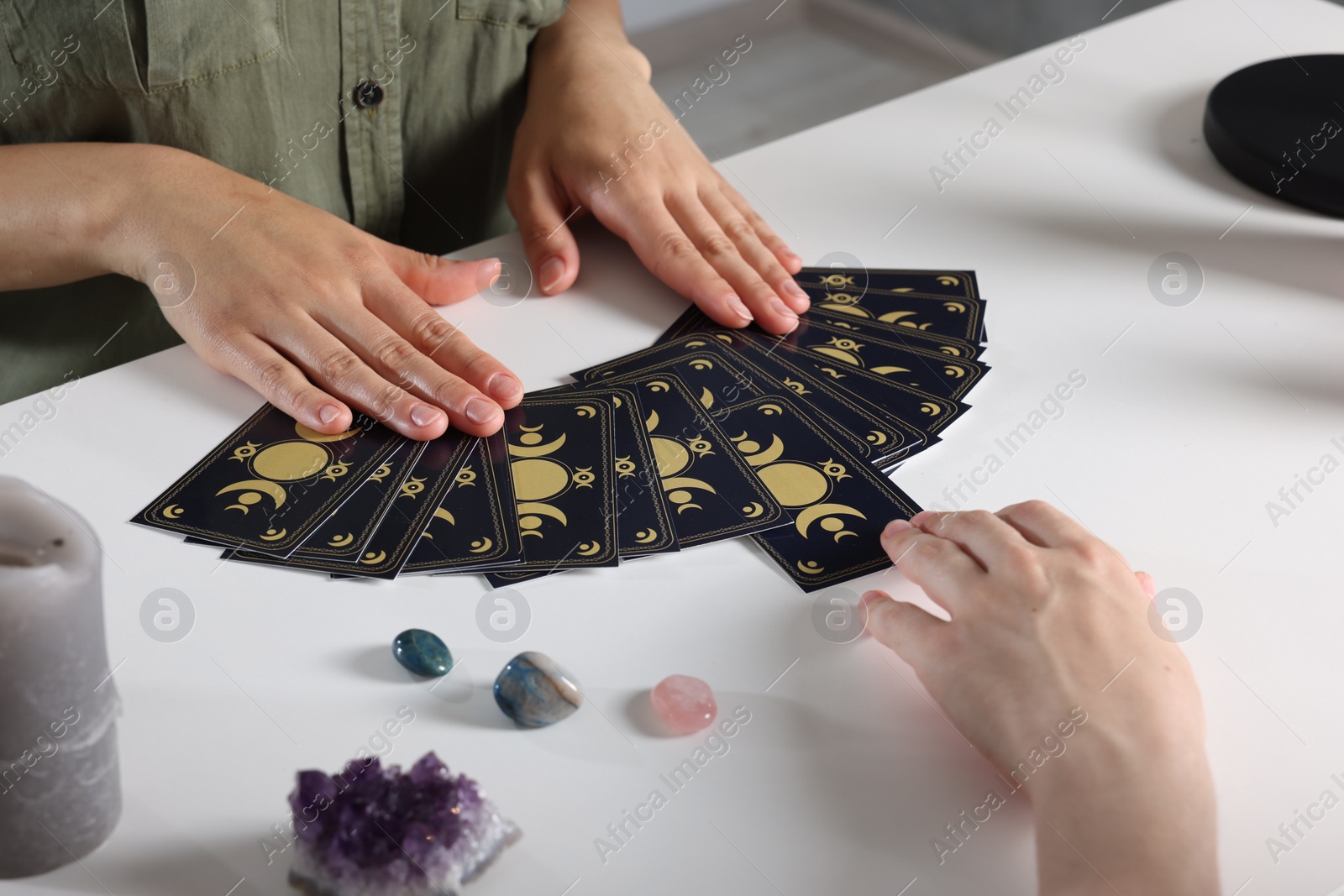 Photo of Astrologer predicting client's future with tarot cards at table indoors, closeup