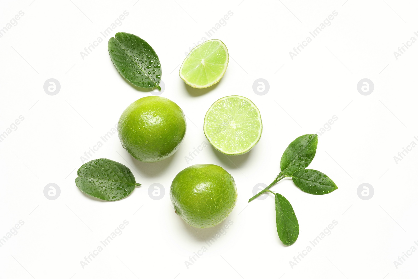 Photo of Whole and cut fresh ripe limes with green leaves on white background, flat lay