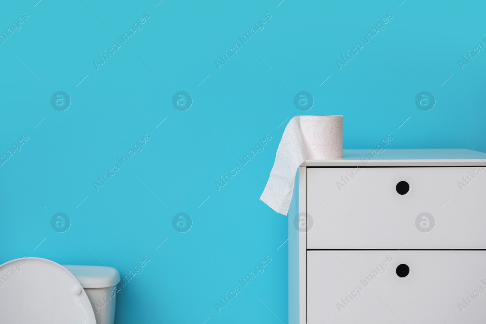 Photo of Toilet paper roll on cabinet in bathroom. Space for text