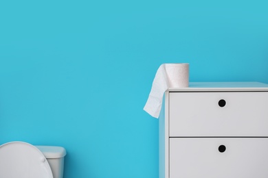 Photo of Toilet paper roll on cabinet in bathroom. Space for text