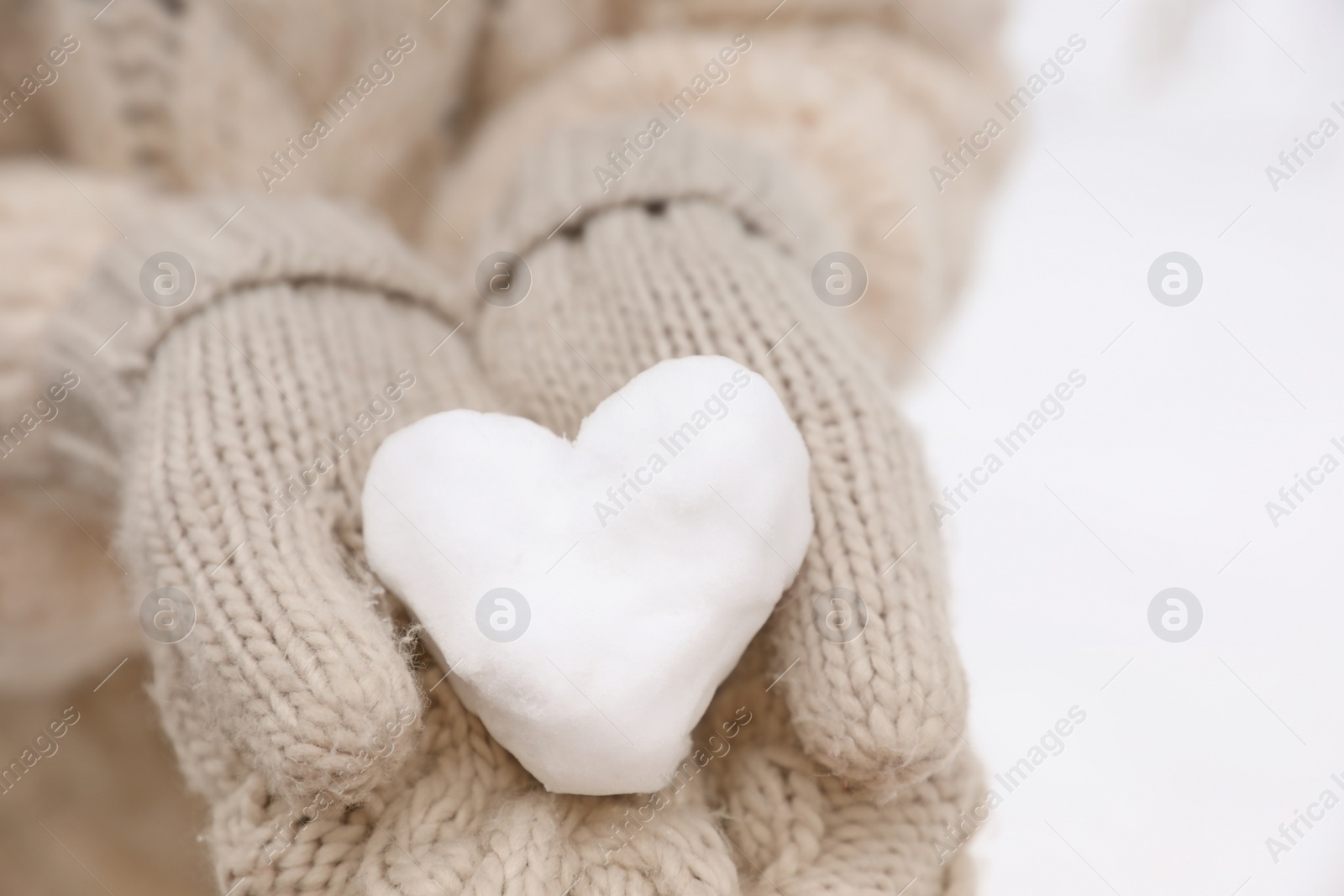 Photo of Woman holding heart made of snow, closeup view