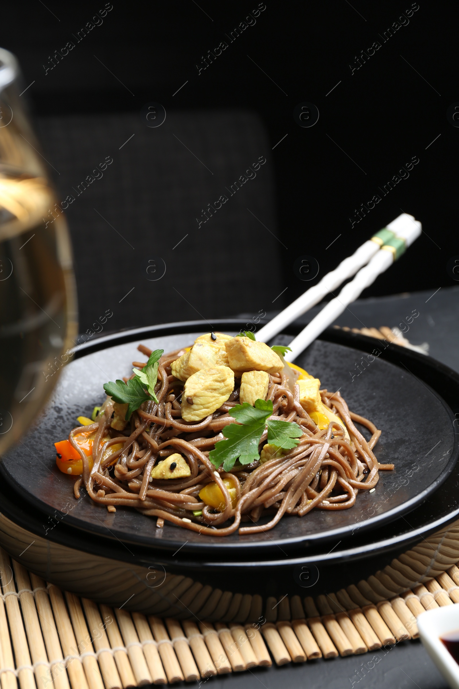 Photo of Stir-fry. Tasty noodles with meat and vegetables served on dark table