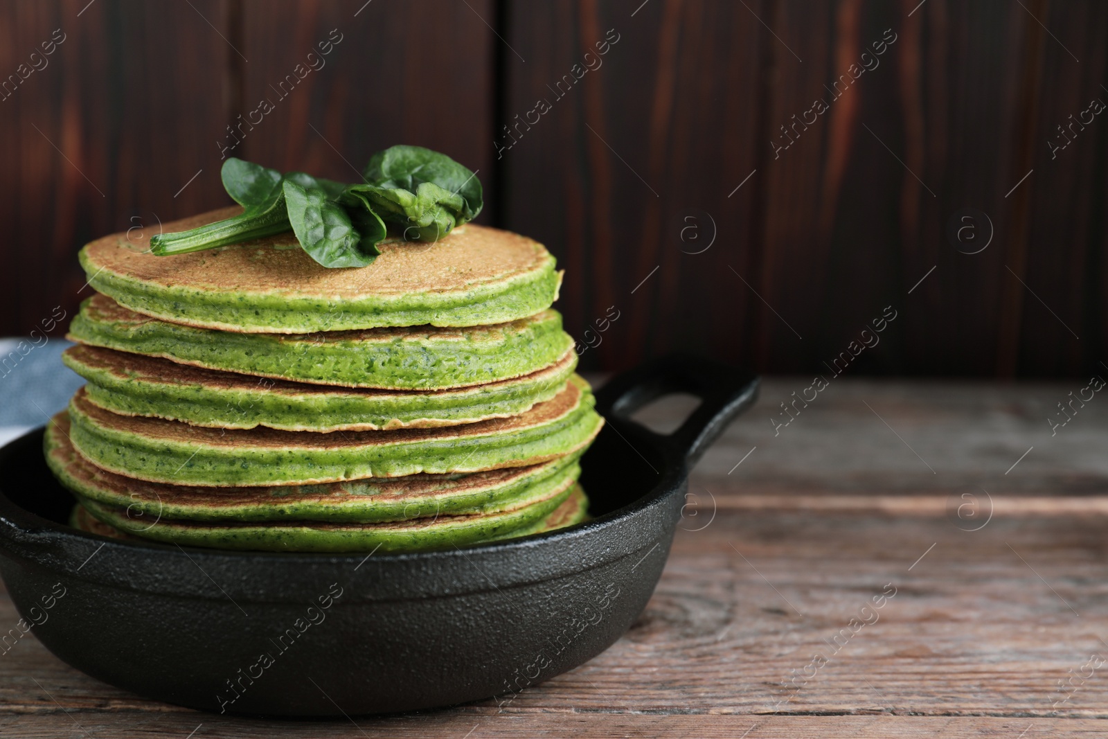 Photo of Tasty spinach pancakes on wooden table, closeup