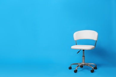 Comfortable office chair on light blue background, space for text